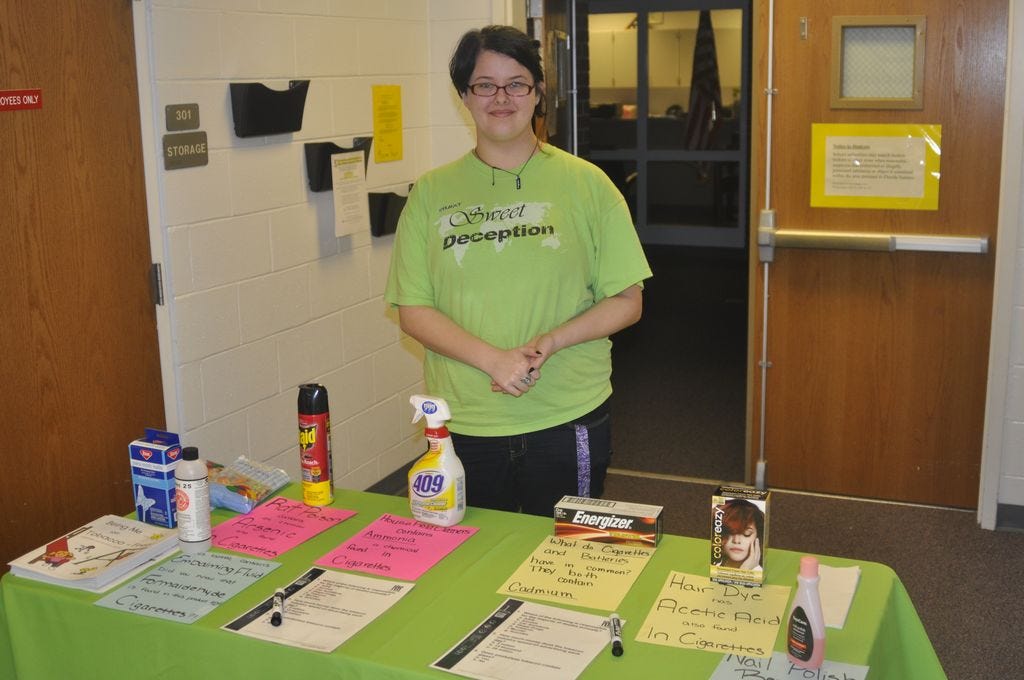 Pace High School student Bailey McKinnell, a PHS SWAT member, mans an informational table during Saturday's Kick Butt event at Avalon Middle School. The displays show which dangerous household chemicals are found within a cigarette.