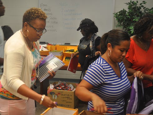Volunteers organize school supplies in backpack for this SundayÂ’s Back to School Bash at the Guy Thompson Community Center.