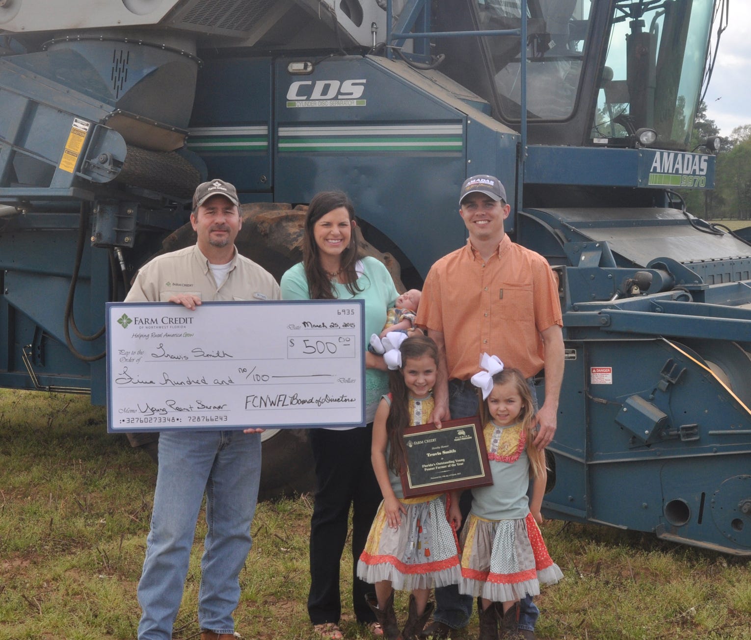 Travis Smith, right, is joined by his young family and Mike Digmon of Farm Credit of Northwest Florida. Smith, a native of Jay, was recently awarded by Farm Credit as ‘Florida’s Outstanding Young Farmer of the Year.’ Joining Smith in the center is his wife Brittany, holding their three-week old son Tate and their two daughters Leah, 6, and Lexie, 5.