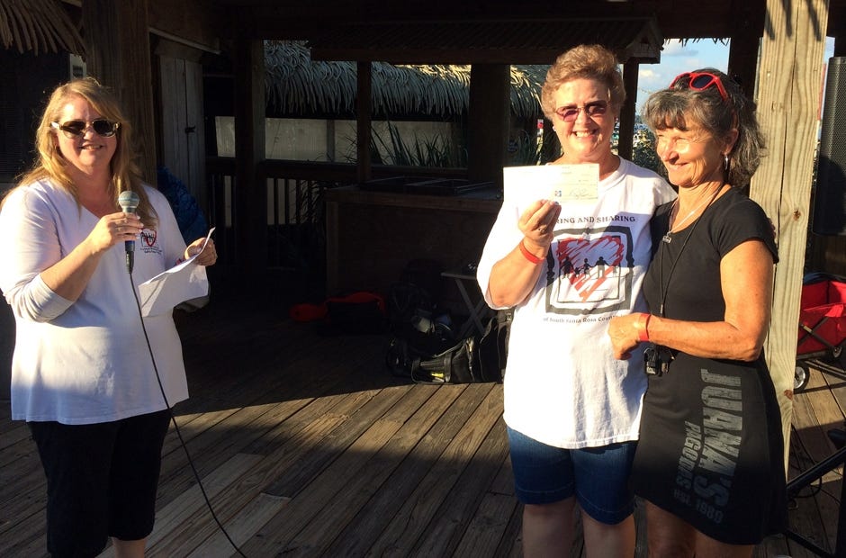 Ann Thompson and Brenda Smith, Caring & Sharing volunteer president and vice president respectively, receive a check from Marie Rudzki, Juana's manager, at a previous Charity Chili Cook-off and Volleyball Tournament Fundraiser. [CONTRIBUTED PHOTO]