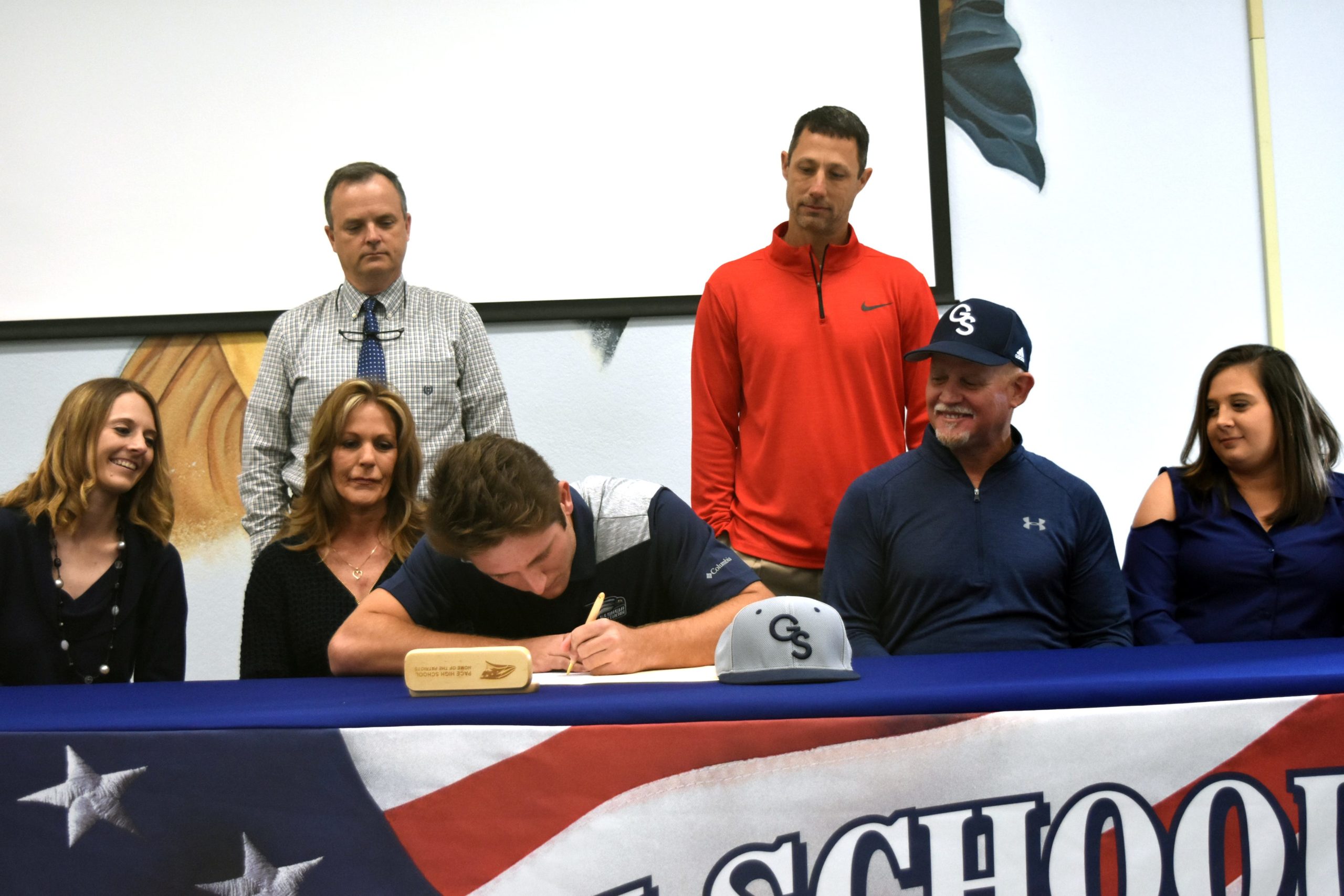 J.C. Peacher signs his letter of intent to play at Georgia Southern University as his immediate family, Pace Principal Stephen Shell and his head coach Jason McBride look on. [RAMON RIOS/PRESS GAZETTE]