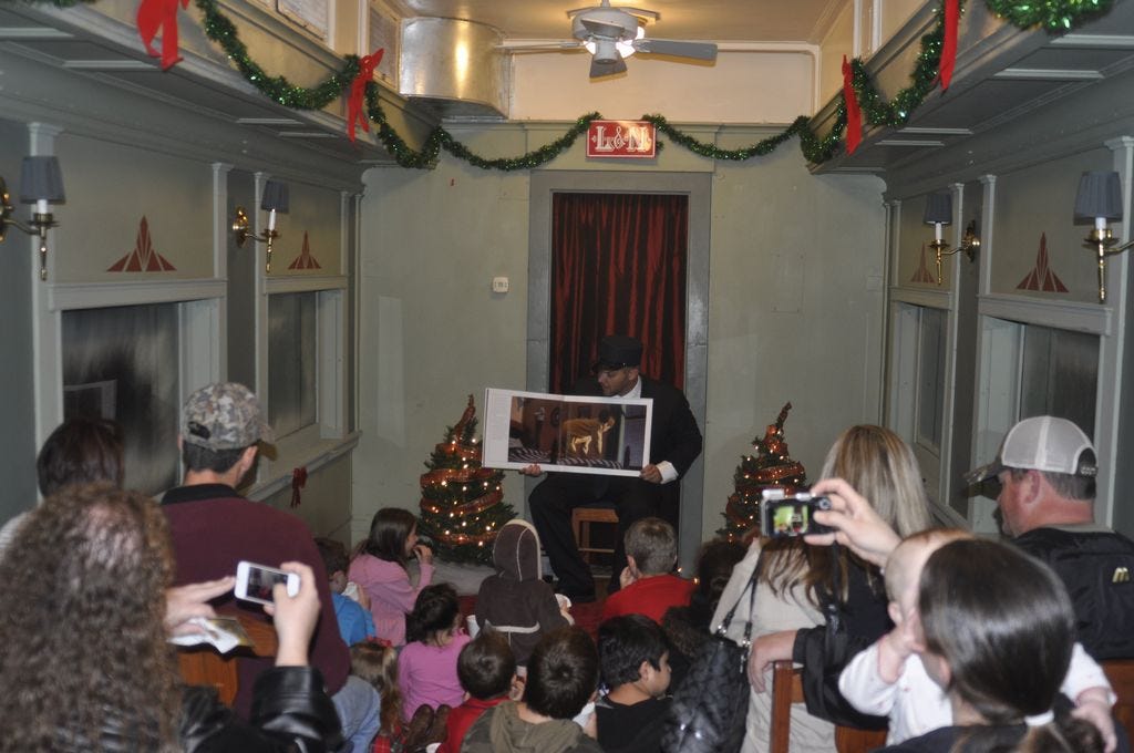 Playing his role as the train conductor, Ryan Sanborn reads the classic children’s book “The Polar Express” written by Chris Van Allsburg in the dining car.