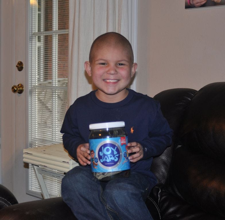 Six-year-old Khai Davidson shows his ‘Joy Jar’ in which he collects funds in order to help out other children dealing with cancer.
